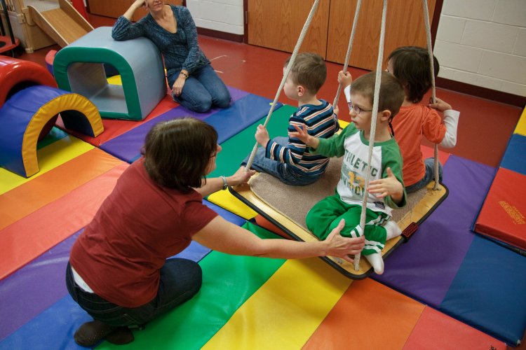 Teacher pushing kids on a swing