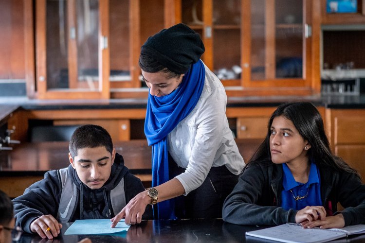 Teacher points something out to seated student