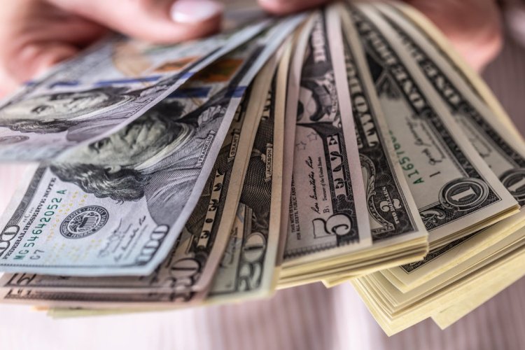 a person holding a handful of American currency