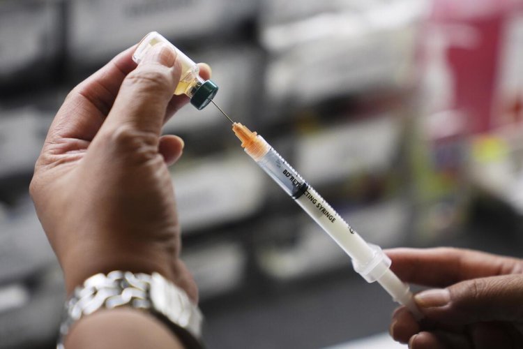 a picture of someone filling up a syringe from a vial