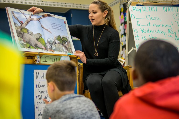teacher reading a book to grade school class