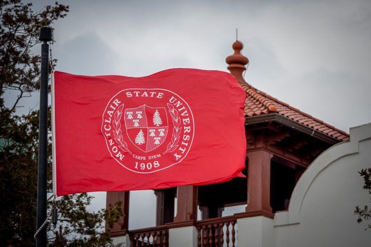 Montclair State University flag - red background with white seal - flying on flagpole