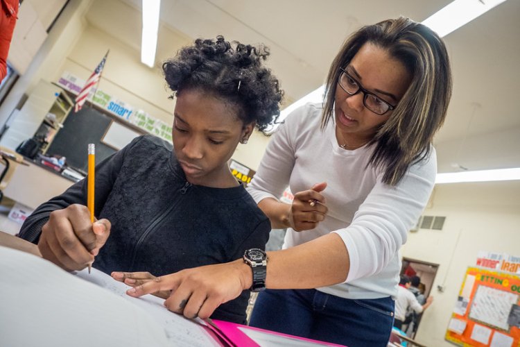 a teacher helps a child over their shoulder