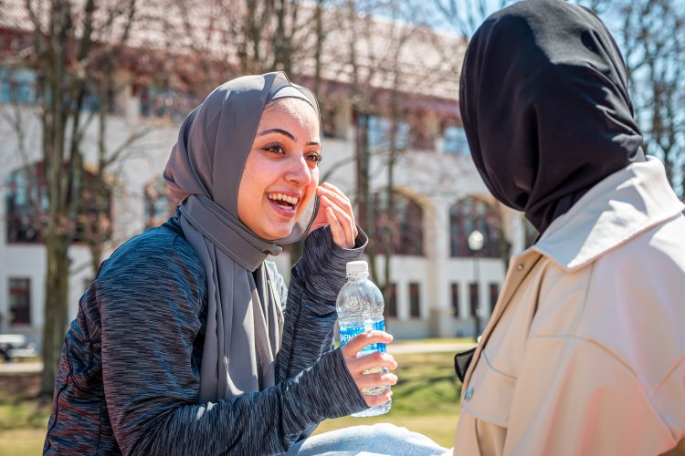two students laughing on quad wearing headdress