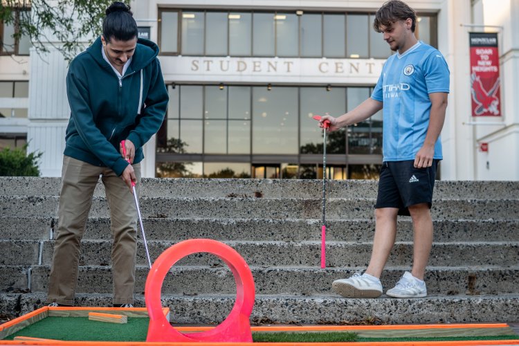 students playing mini golf outside student center
