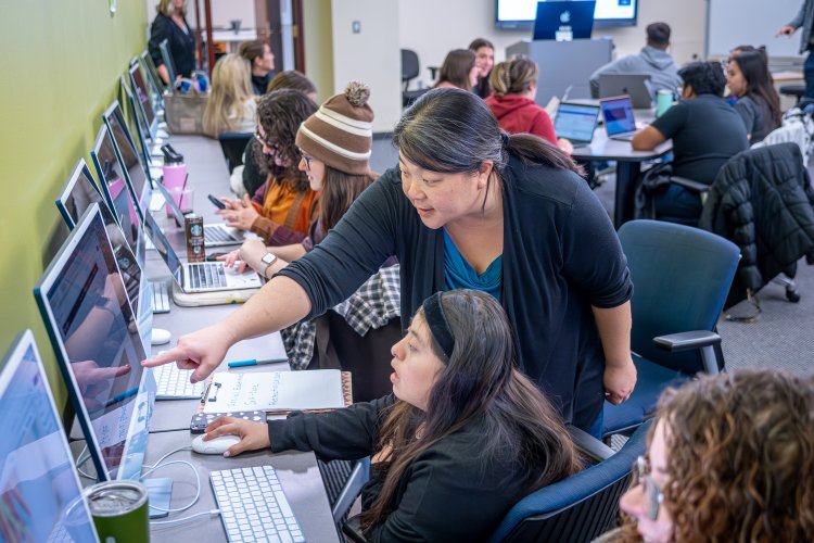 a teacher helps a student at the computer