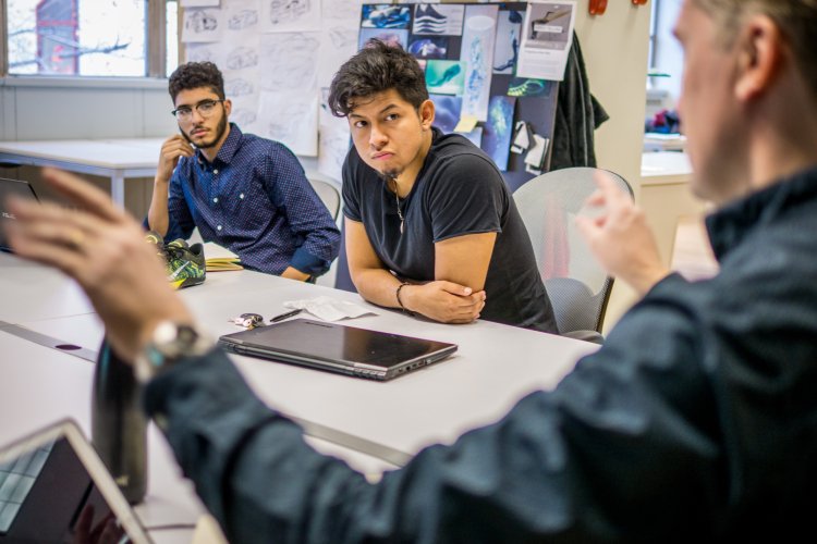Two male students listening to their professor in a classroom