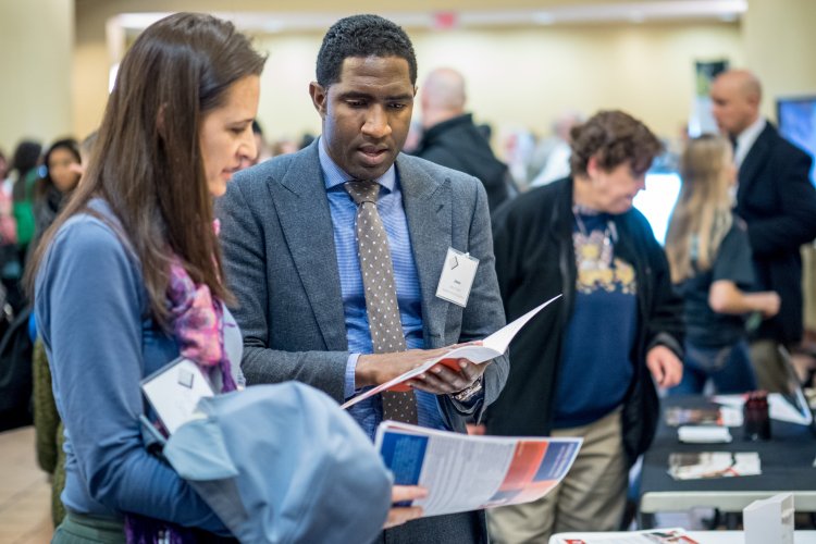 Two people talking in front of a conference booth table 