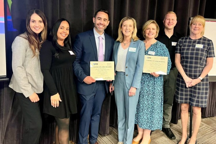 Seven professionals standing side by side holding certificates