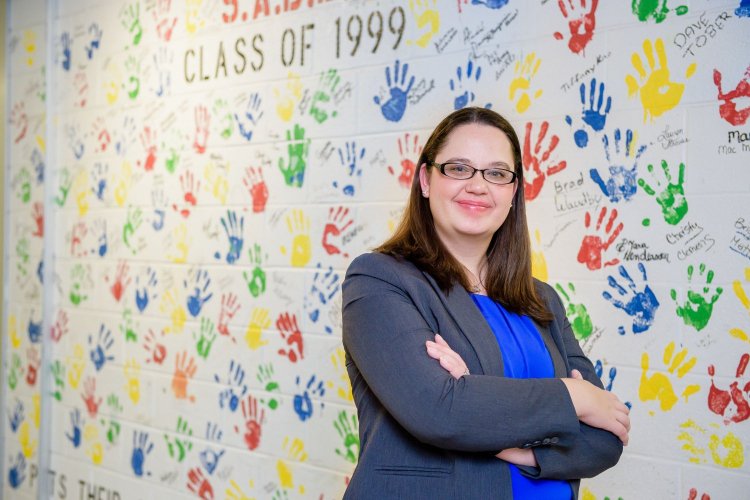 Teacher in front of wall with painted handprints 