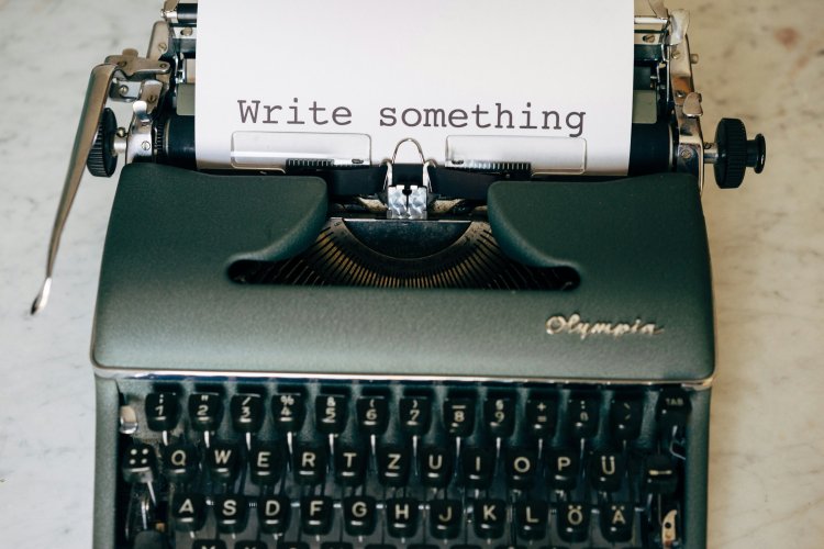 A manual typewriter with a page that says "Write something"