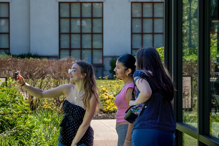 three students taking a selfie on campus