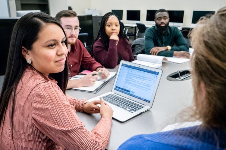 a group of students work around a computer