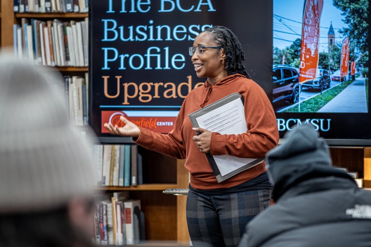 Woman standing in front of television speaking to audience
