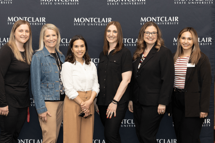 Student Success Team pose in front of a step and repeat.