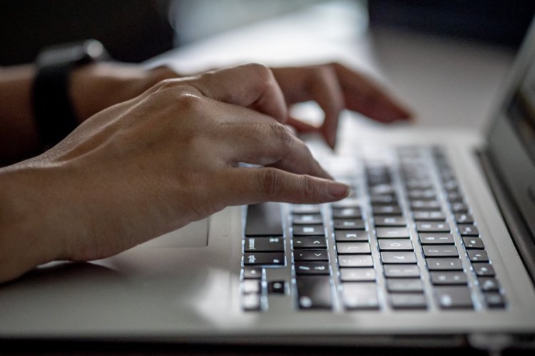 Hands typing on laptop keyboard