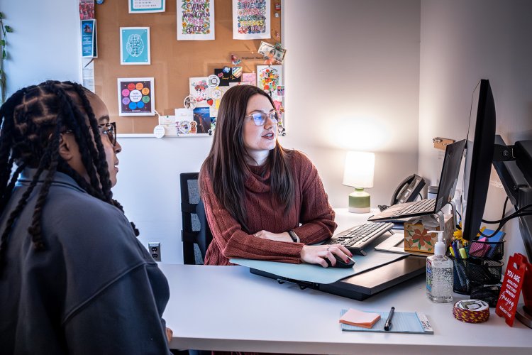 photo of career advisor Macayla Mack with a student in her office for an appointment, they are looking at a computer