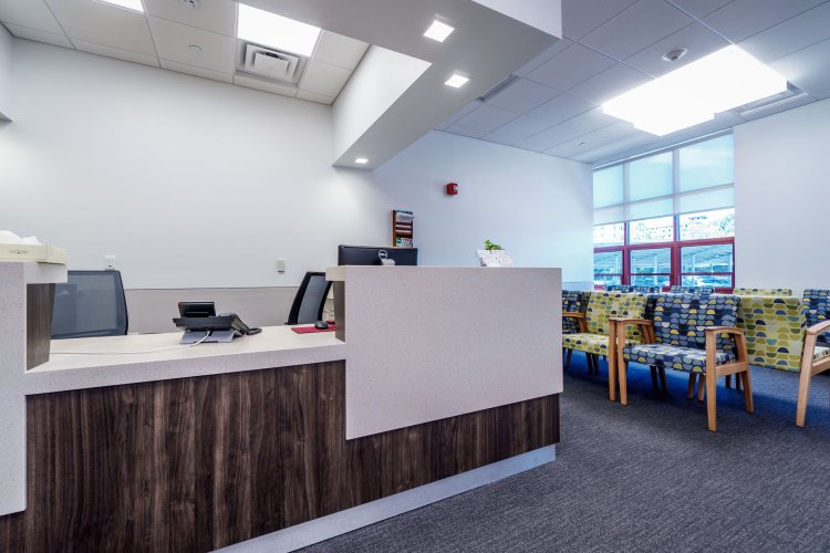 Interior of the Center for Clinical Services. There are chairs in the waiting area and a receptionist's desk.