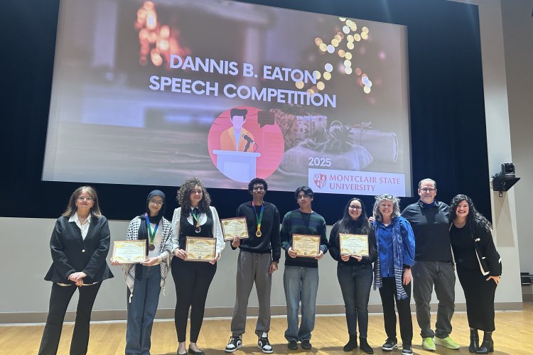 Speech competition winners holding their certificates on stage, smiling.