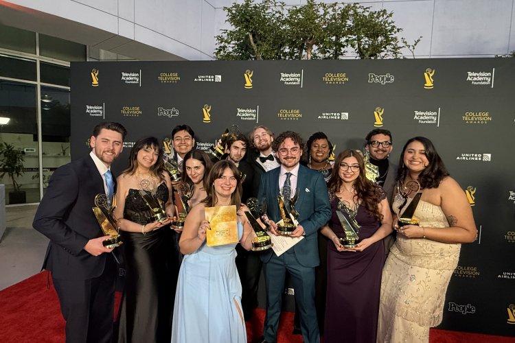 Students pose for a photo with Emmy awards on the red carpet.