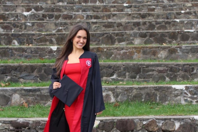 Alum Claudia Challender posing in graduation gown.