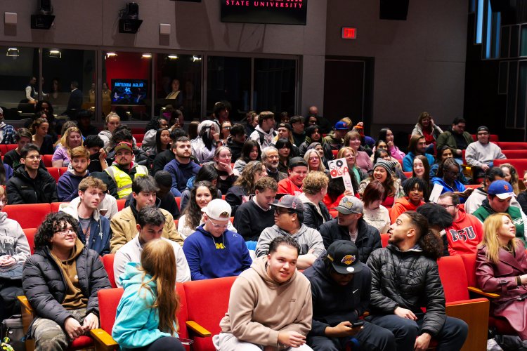 Students in auditorium seats conversing.