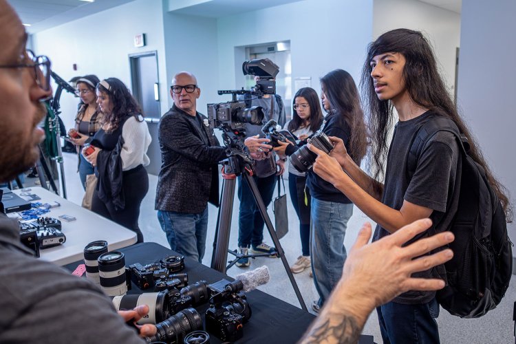 Student checking out a camera as a professional explains its features.