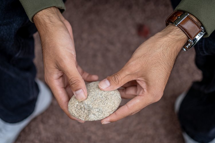 Student holding a rock in the quiet memory and reflection garden.