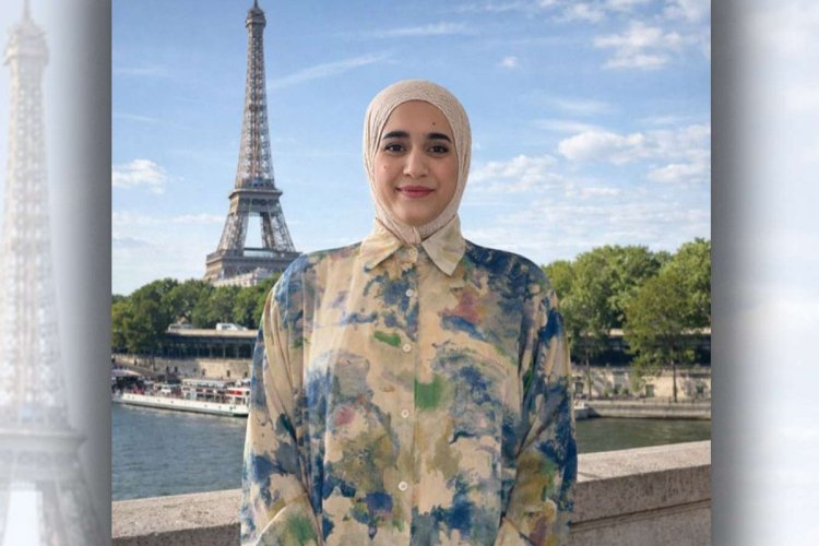 Headshot of Ptissem Assou standing in front of the Eiffel Tower