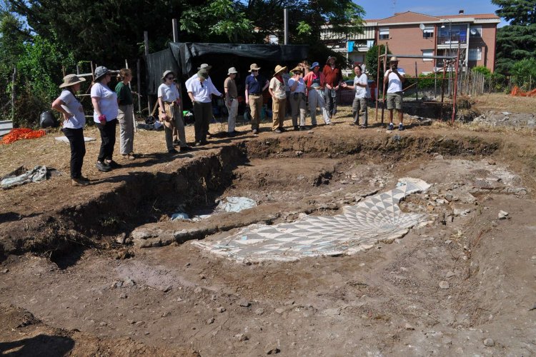 Archaeologists examine the remains of a patterned mosaic floor at an excavation site
