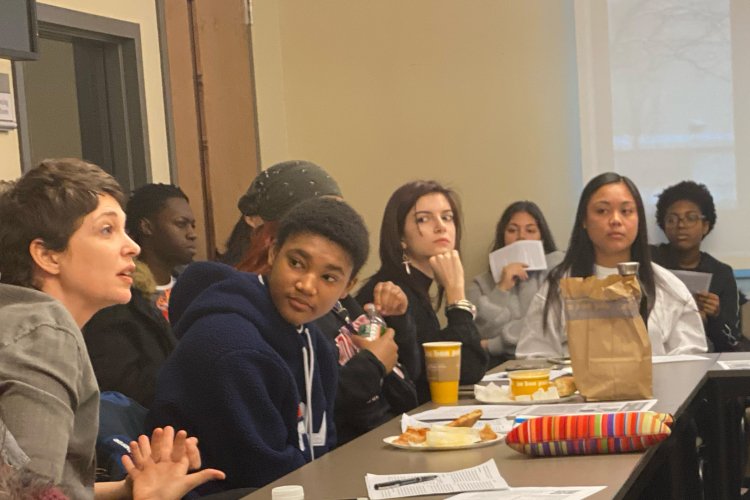 in a full room, on person is speaking during Philosophy for Lunch as others look on