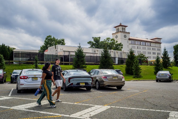 two students walking on a cross walk with a car in the background