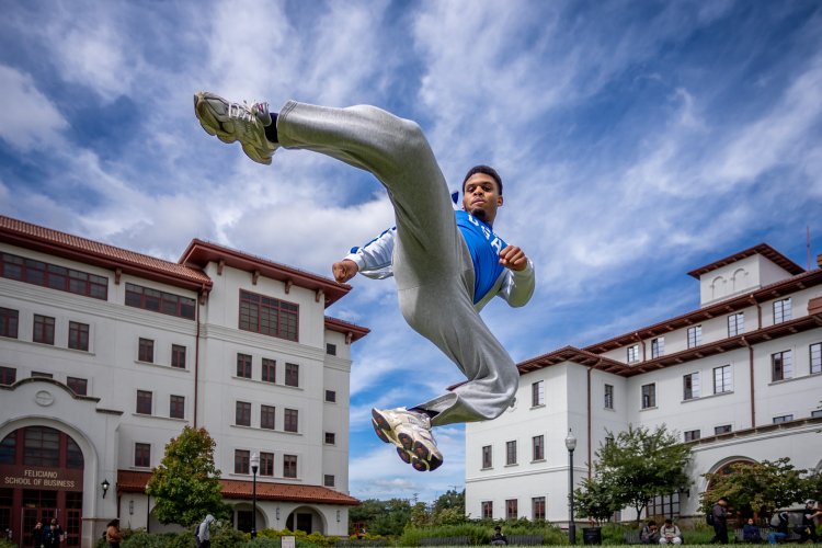 Cameron Massay demonstrates a kick used in Taekwondo on a college campus.