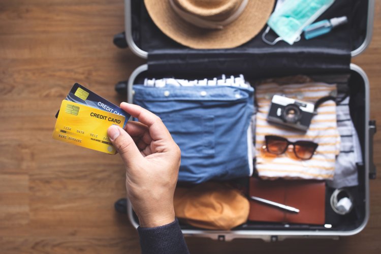 Person holding credit cards over a suitcase 