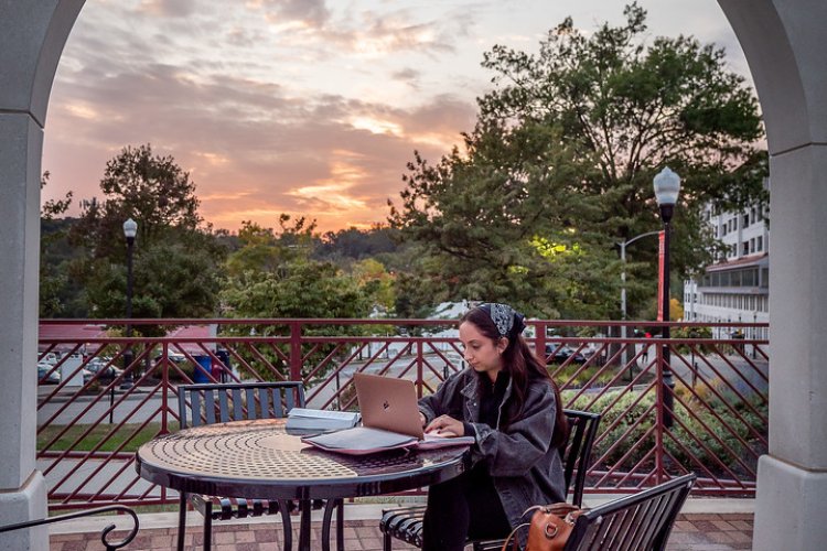Online learner working on laptop in an outdoor setting