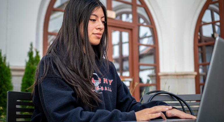 a student works on her laptop in the courtyard