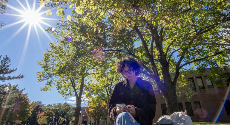student sitting outside with the sun shining