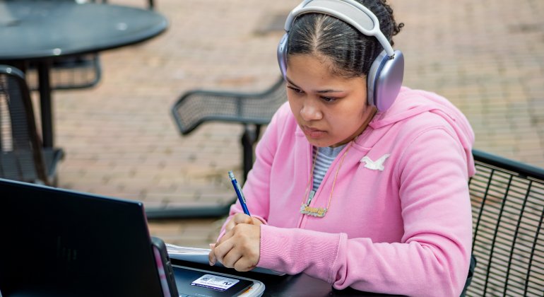 student wearing headphones doing work on laptop