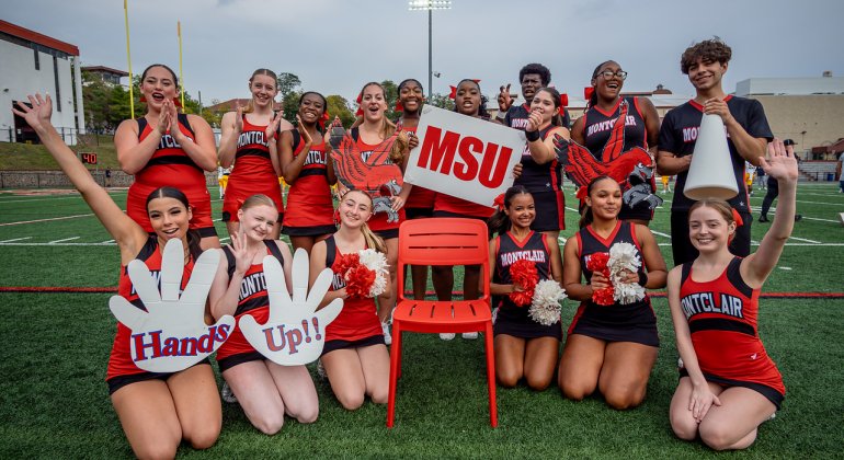 Cheerleaders on the field with a red chair 