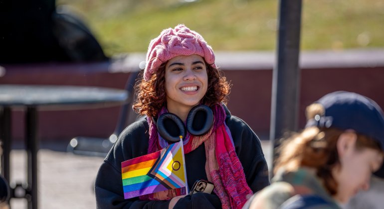 student smiling with LGTBQ+ flag 