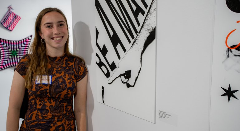 Student standing next to their artwork in the Finley Gallery