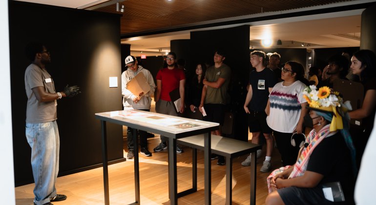 Montclair State University student guiding a class through an exhibition.