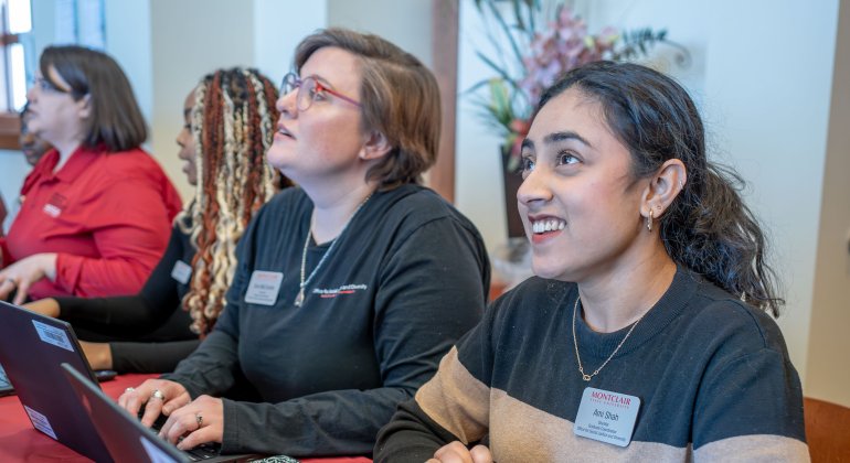 Graduate student employee tables a campus event with colleagues.