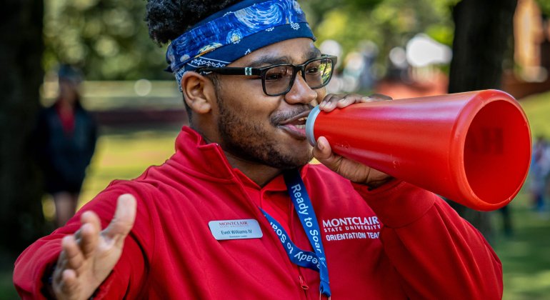 Student worker speaks into a red megaphone at orientation.