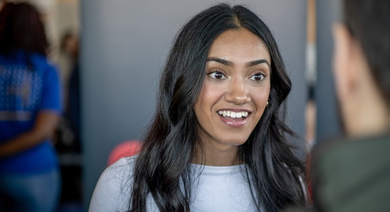 Student smiles while speaking with a representative at a career fair.