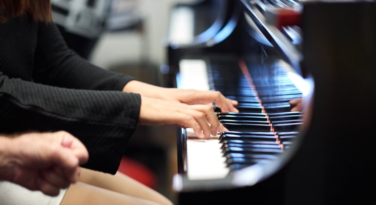 Piano keys with student's hands playing piano