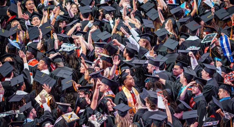 Graduates wave to loved ones from seats