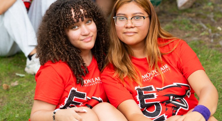 two eof students sitting on the ground