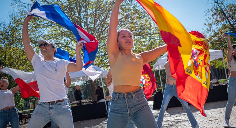 Students dancing with Latinx flags