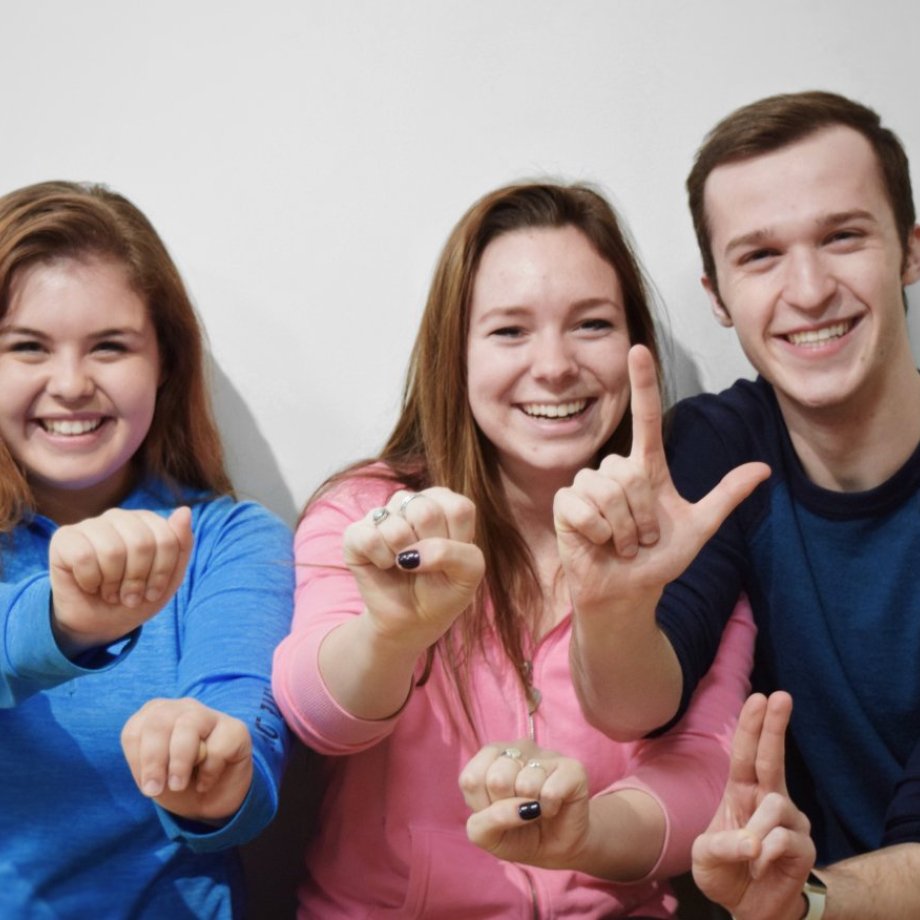 Three people signing "I Love You" in American Sign Language